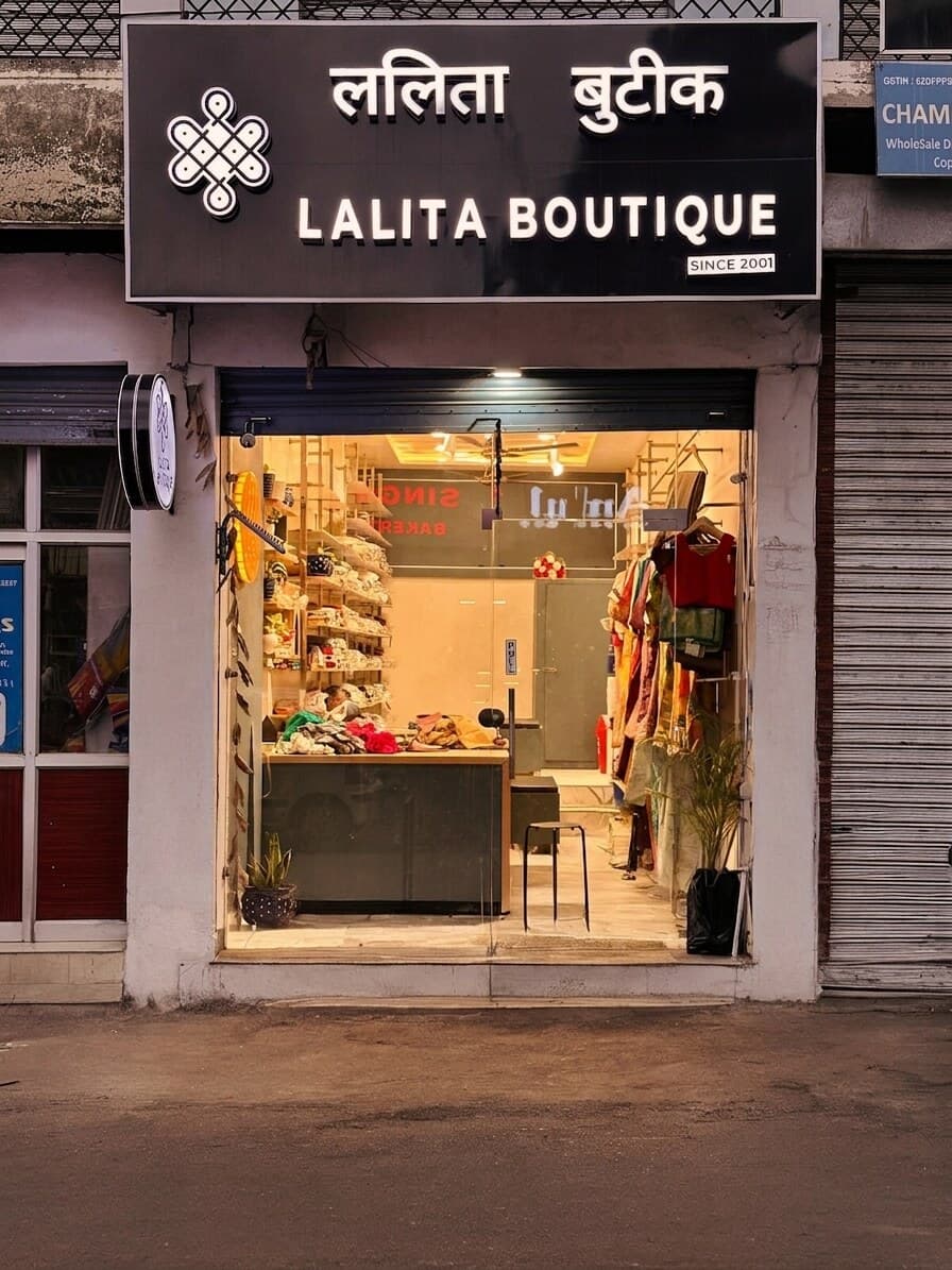 Lalita Boutique storefront at dusk, lit signage, interior visible through glass.